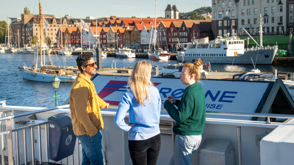 Gjester hygger seg på fjordcruise fra Bergen med Bryggen i bakgrunnen