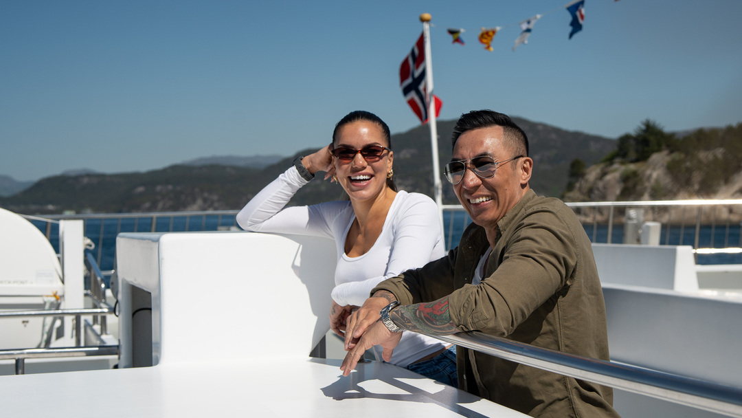 to smilende gjester nyter solen ute på dekk under et av Rødnes unike cruise fra Stavanger