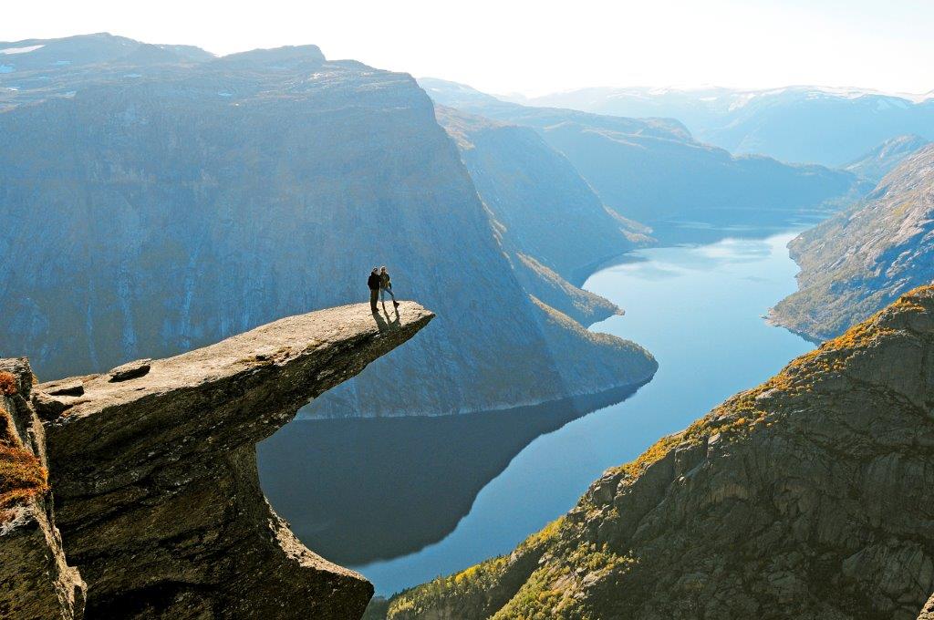 Hikers standing on the famous Trolltunga rock, overlooking a the beatiful Ringedalsvatnet lake, a must-visit destination near the Hardangerfjord.