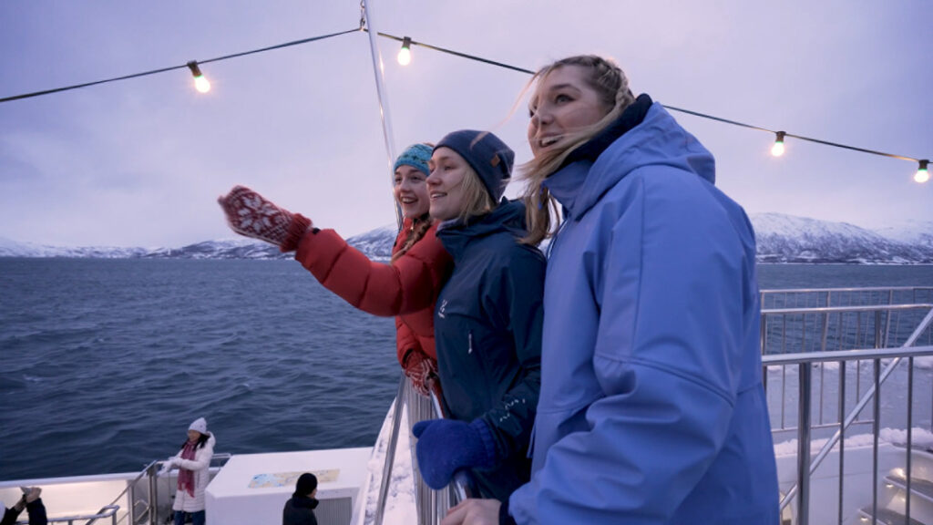 3 jenter står på det øverste dekket om bord et hvalsafari og speider etter knølhval og spekkhuggere.