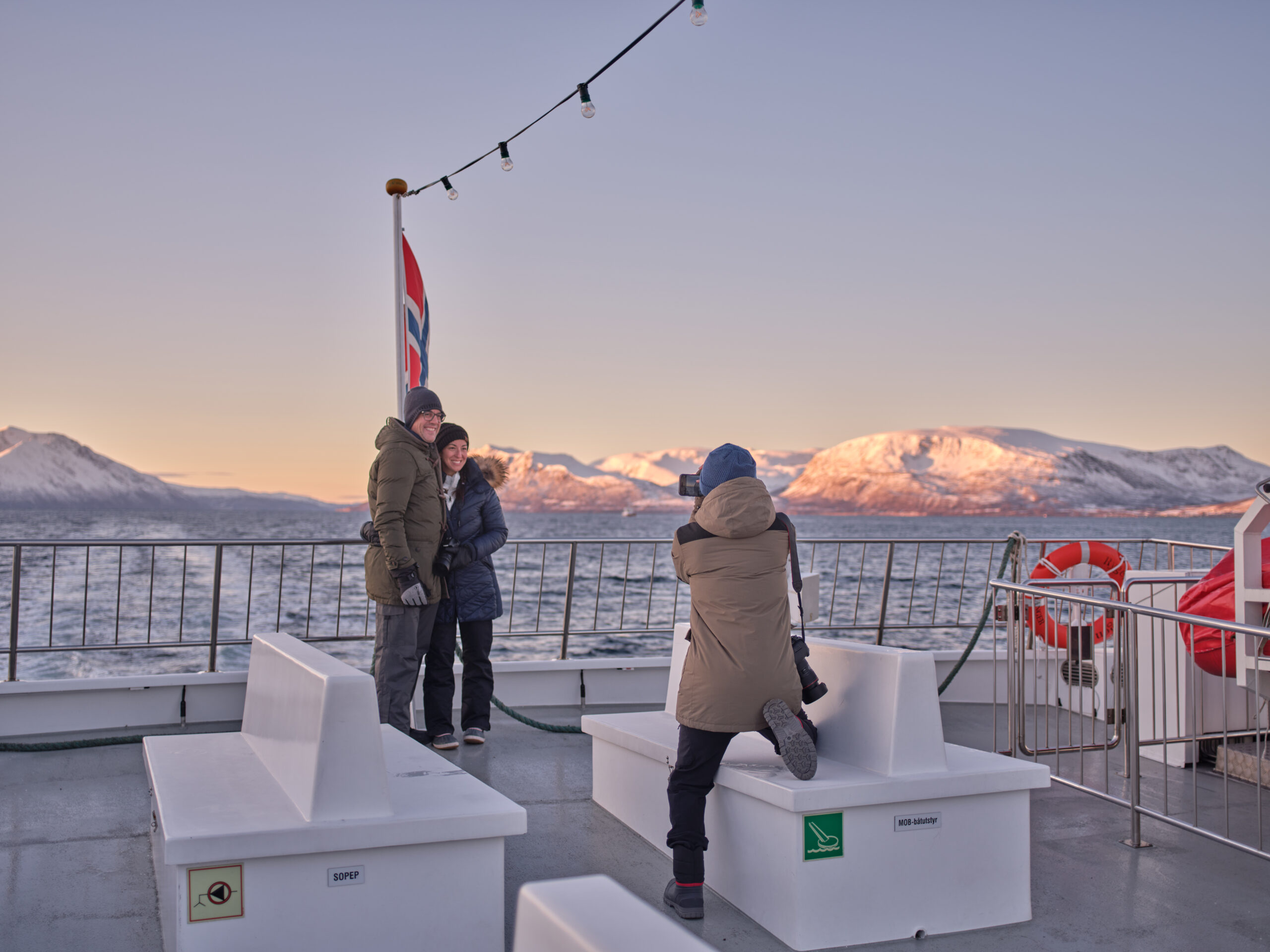 A winter fjord landscape in Tromsø with calm waters and snow-covered mountains in the background, capturing the serene Arctic atmosphere.