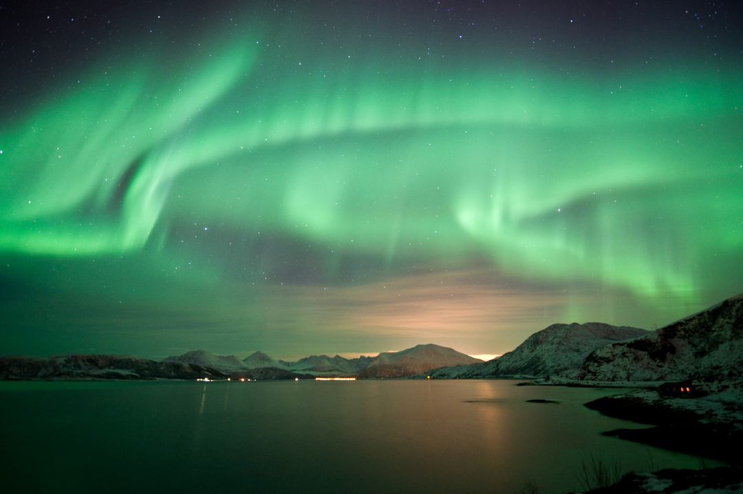 Nordlys danser over himmelen og fjellene i Tromsø