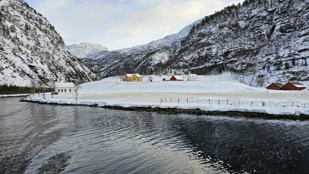 Se de sjarmerende, fargerike husene langs fjorden på vei til Mostraumen. En vakker blanding av norsk natur og kultur.
