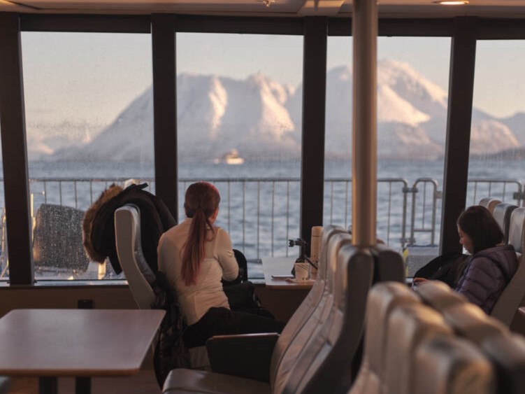 Passengers enjoying panoramic views of the Arctic fjords from the lounge of a comfortable catamaran near Tromsø