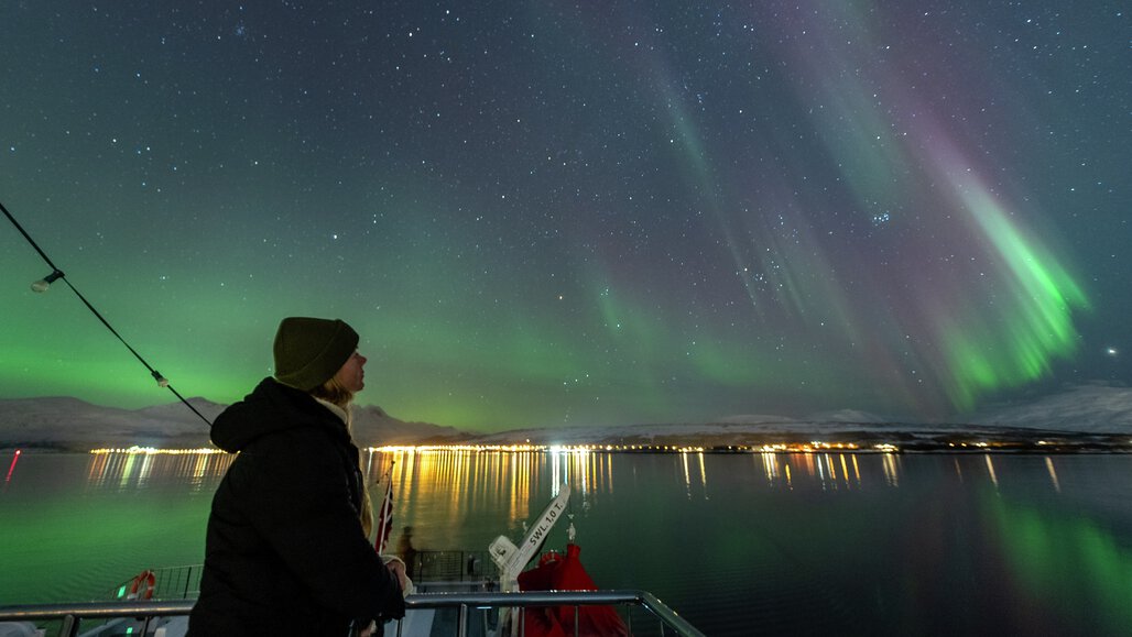 Woman looking up at the Northern Light and the clear Arctic sky