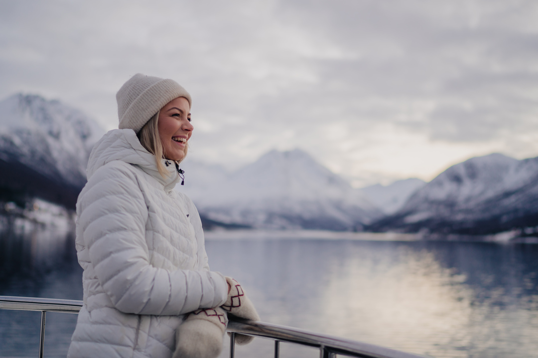 A smiling girl overlooking the beautiful arctic landscapes from a half day boat tour in Tromsø