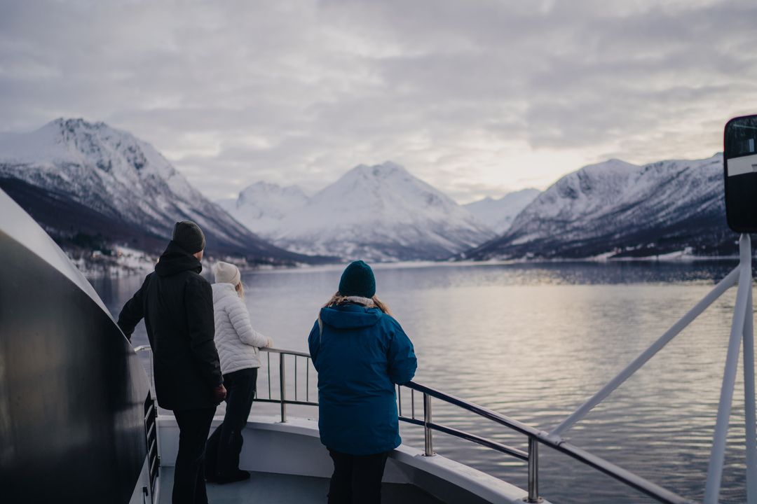 A breathtaking fjord in Tromsø with a tranquil sea reflecting snow-covered mountains, perfectly capturing the essence of an Arctic fjord cruise experience