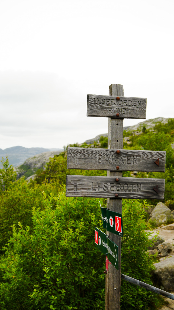 A wooden hike sign showing the way to the top of Preikestolen or other hike routes.