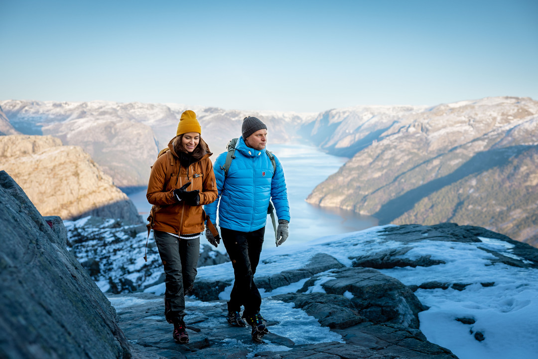 A couple enjoying the world-famous Pulpit Rock from two breathtaking perspectives: first from the tranquil waters of the Lysefjord and then from the Preikestolen plateau, rising 604 meters above.