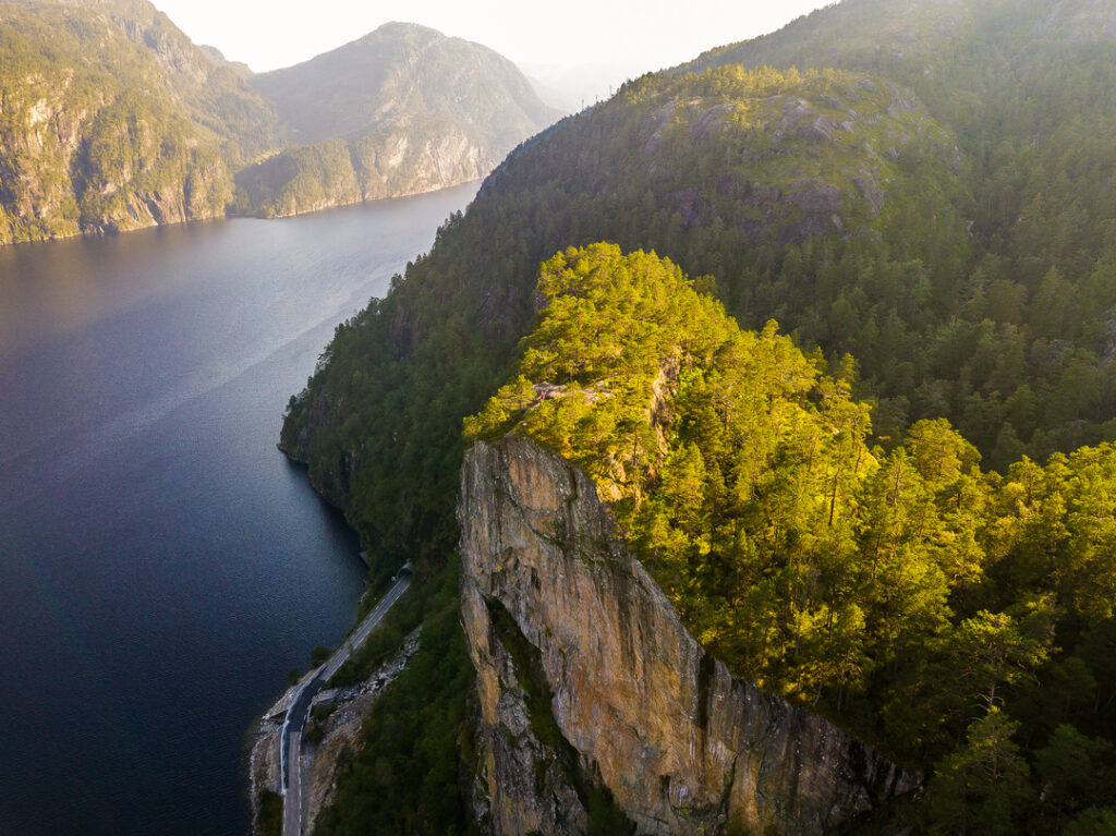 Dramatic aerial view of Mo fjord with steep cliffs (slottet) and sunlight highlighting the lush green vegetation.