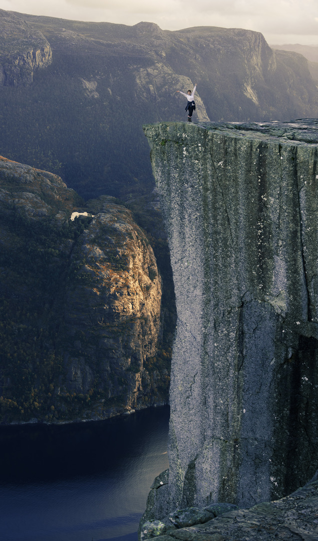 A woman celebrating that she has reached the top. Standing on the very edge of Preikestolen