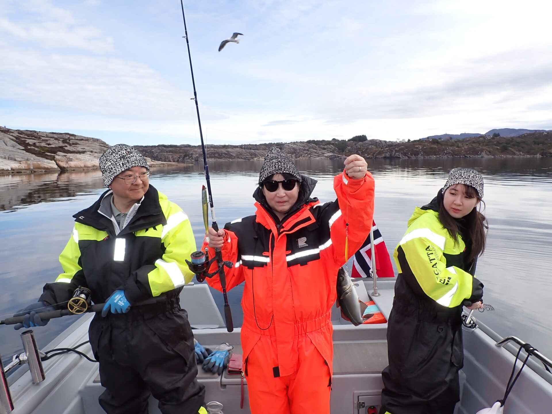 Group enjoying a fjord fishing tour near Stavanger in warm suits