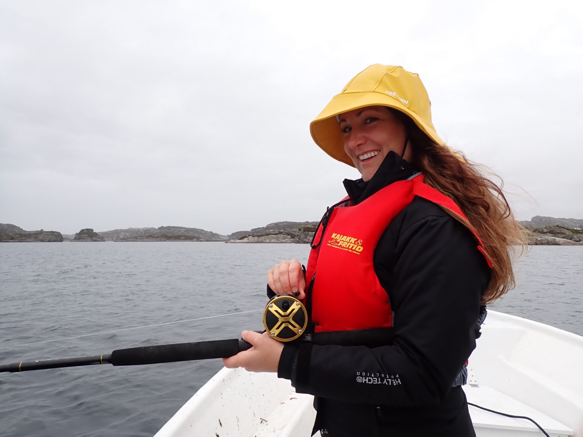 Woman fishing in Lysefjord with a big smile and red life vest