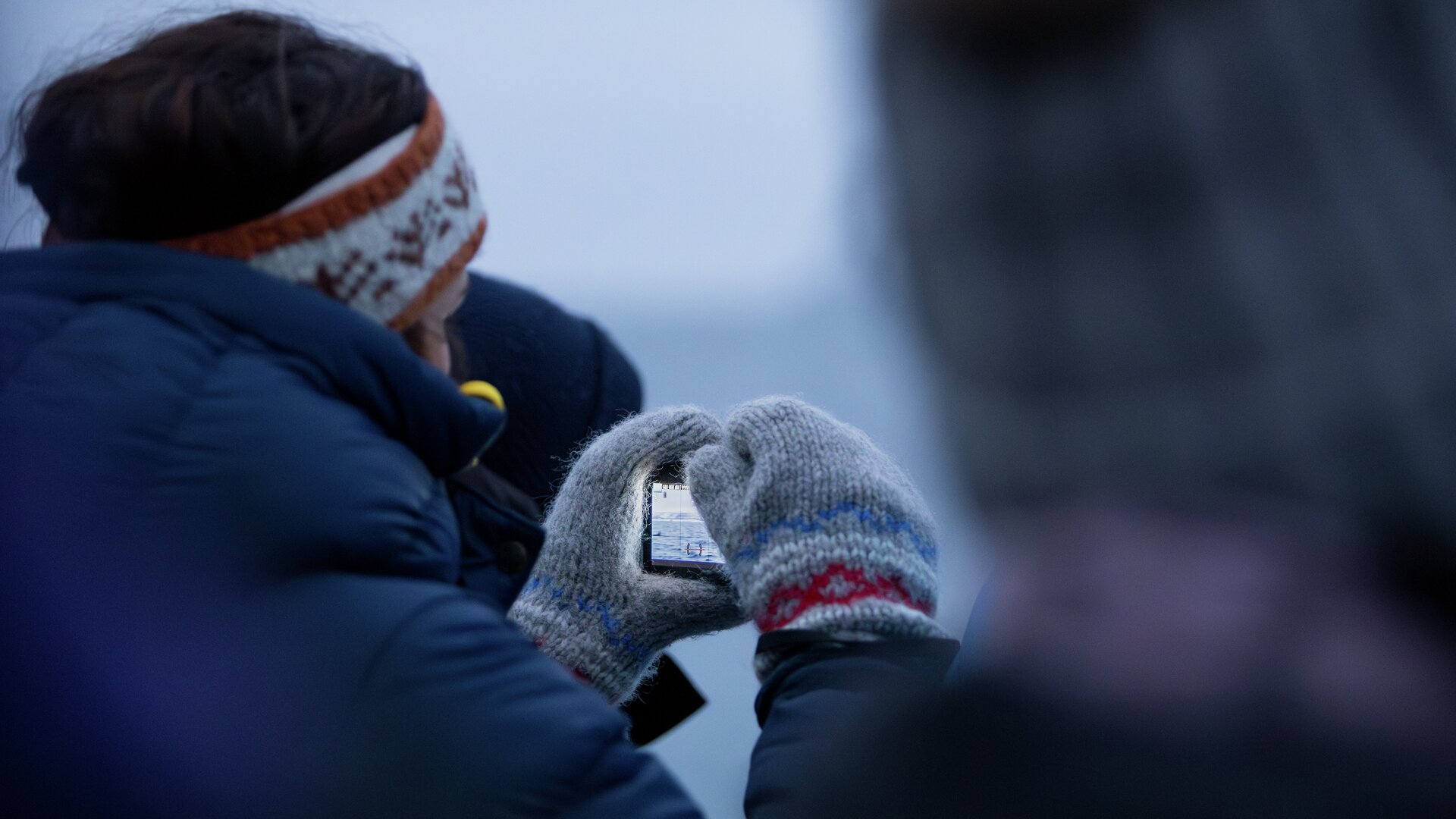 Guest taking a photo over the fjord during a sustainable whale watching tour in Tromsø. You can see the orcas playing in the ocean.