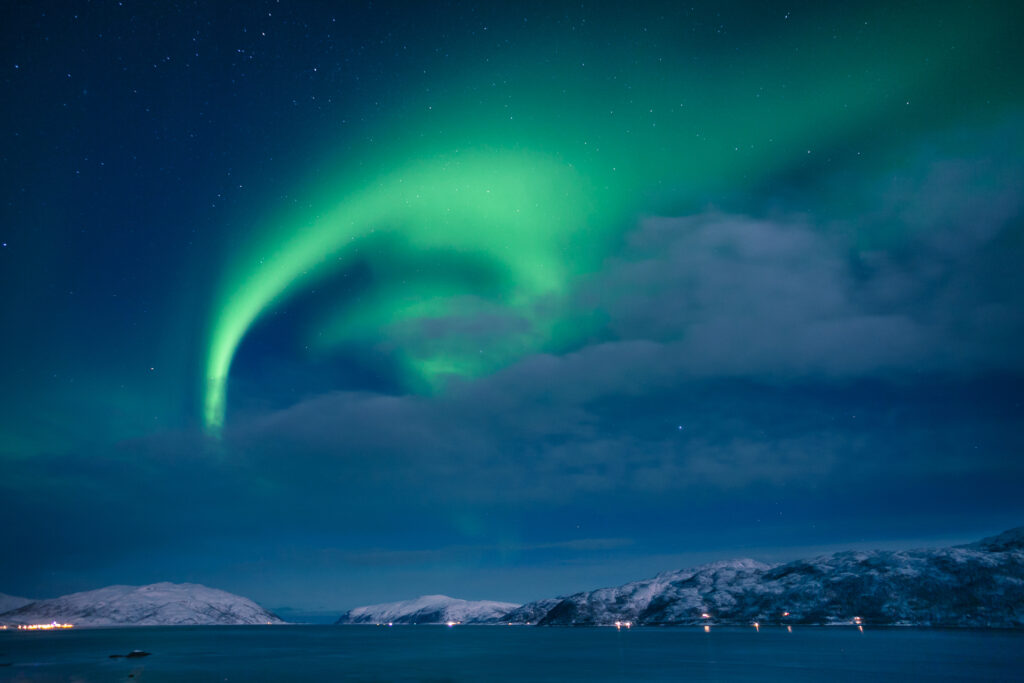 Northern Lights partially visible through a partly cloudy Arctic sky.